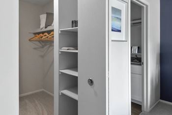 A white closet with a mirror and shelves.